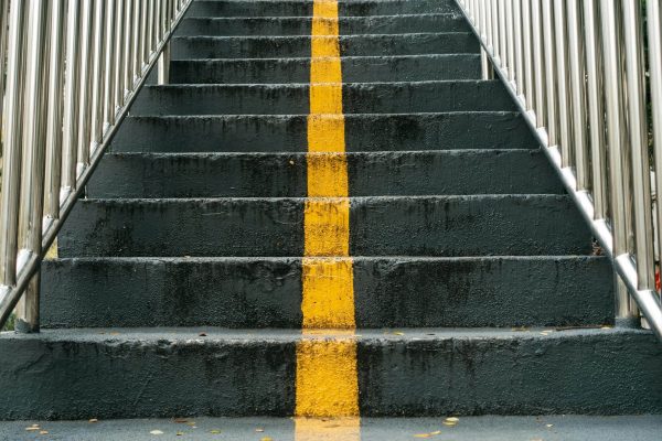 Close-up of urban staircase featuring a prominent yellow line and metal railings.